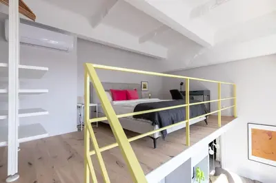 a bedroom with a bunk bed with a yellow railing at Artsy Design Loft - Hip District Uptown Vilnius in Vilnius