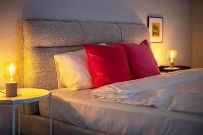 a bed with red and white pillows and two lamps at Artsy Design Loft - Hip District Uptown Vilnius in Vilnius