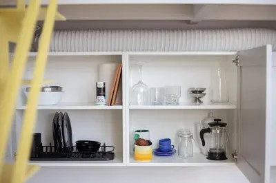 a white cabinet filled with lots of kitchen items at Artsy Design Loft - Hip District Uptown Vilnius in Vilnius