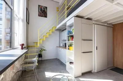 a room with a staircase with white cabinets and yellow stairs at Artsy Design Loft - Hip District Uptown Vilnius in Vilnius