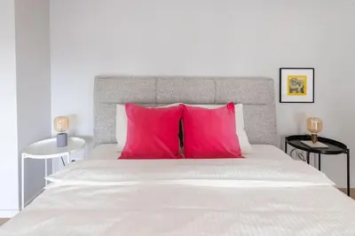 a bedroom with a large bed with pink pillows at Artsy Design Loft - Hip District Uptown Vilnius in Vilnius