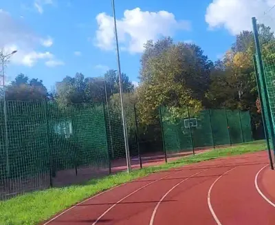a tennis court with a fence and a basketball hoop at Cozy apartment Akropolis in Vilnius