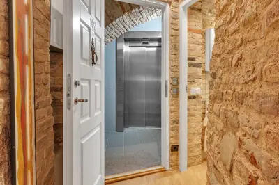 a bathroom with a walk in shower next to a stone wall at Historic & modern Arch-Studio - ArcLoft07 in Vilnius