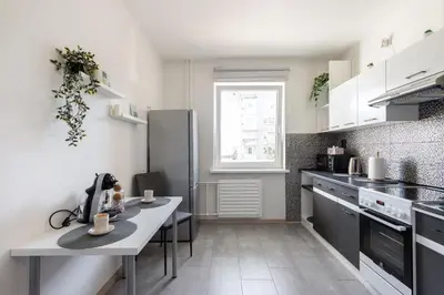 a kitchen with white cabinets and a table with cups on it at Spirit Of 70s Apartment in Vilnius