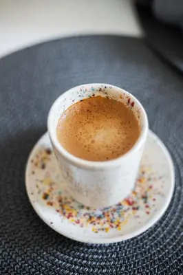 a cup of coffee on a plate with sprinkles at Spirit Of 70s Apartment in Vilnius