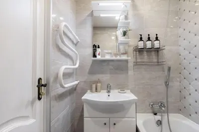 a white bathroom with a sink and a shower at Spirit Of 70s Apartment in Vilnius