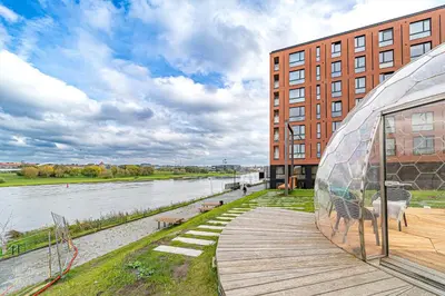 a building with a glass dome next to a river at River Park Apartment in Kaunas