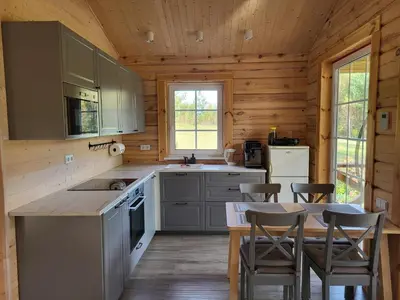 a kitchen with a table and chairs in a cabin at Pine Valley Villa - beautiful nature, jacuzzi, sauna, cozy log house in Inturkė