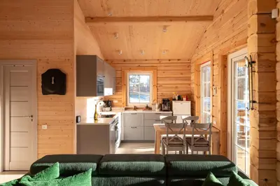 a kitchen and living room in a log cabin at Pine Valley Villa - beautiful nature, jacuzzi, sauna, cozy log house in Inturkė