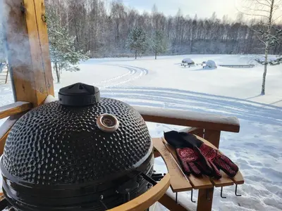 a grill sitting on a table in the snow at Pine Valley Villa - beautiful nature, jacuzzi, sauna, cozy log house in Inturkė