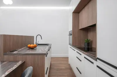 a kitchen with white cabinets and a counter with oranges on it at Modern Apartment in the heart of Vilnius Old Town with free parking by URBAN RENT in Vilnius