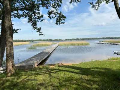 a dock on a lake with a boat in the water at Šarkos sodyba in Miežonys