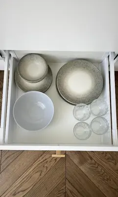 three plates and bowls in a white drawer at Sunrise Uzupis Apartment in Vilnius