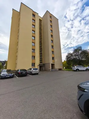 a large building with cars parked in a parking lot at Mocha Apartment in Druskininkai