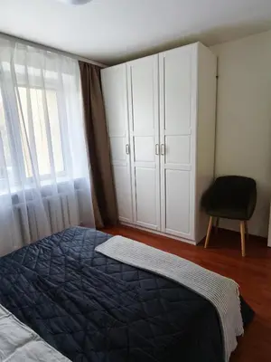 a bedroom with a bed and a closet and a chair at Mocha Apartment in Druskininkai