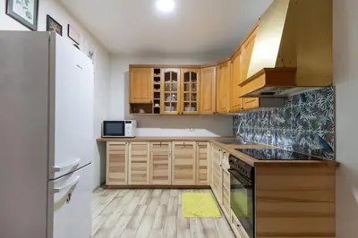 a kitchen with wooden cabinets and a refrigerator at Vilnius Pinewood Apartment in Vilnius