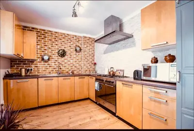 a large kitchen with wooden cabinets and a microwave at Blue Hound Cottage in Kaunas