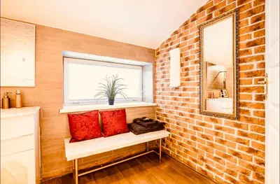 a brick walled bathroom with a window and red pillows at Blue Hound Cottage in Kaunas