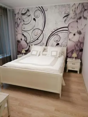 a bedroom with a white bed and a floral wall at Privatus 2kambariu butas in Birštonas