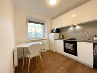 a small kitchen with a table and chairs and a sink at IG Apartments in Karmėlava