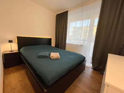 a bedroom with a bed with green sheets and a window at IG Apartments in Karmėlava