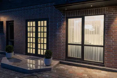 a brick building with glass doors and potted plants at Luxury villa with sauna in the pine forest close to Vilnius city centre in Vilnius