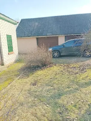 a blue car parked in front of a garage at Via baltica in Degėsiai