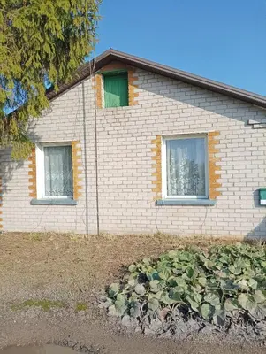 a brick house with two windows in a yard at Degesiai in Degėsiai
