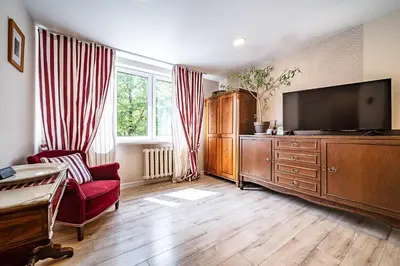 a living room with a tv and a red chair at Thibo Apartamentas in Šiauliai