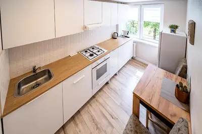 a kitchen with white cabinets and a sink at Thibo Apartamentas in Šiauliai