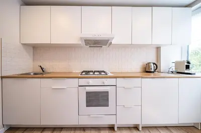 a white kitchen with white cabinets and a sink at Thibo Apartamentas in Šiauliai