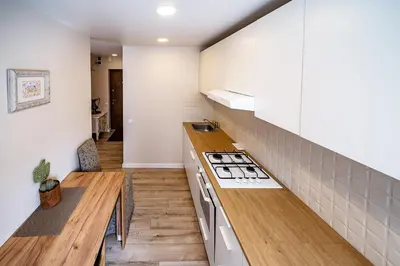 a kitchen with white cabinets and a wooden counter top at Thibo Apartamentas in Šiauliai