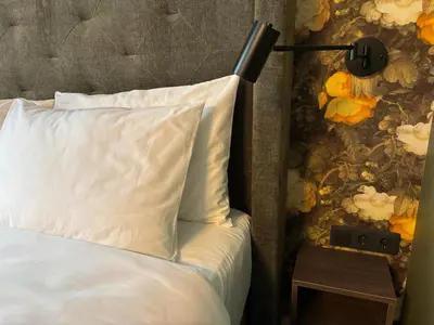 a bed with a white pillow and a lamp on a table at Durpyno 3c SELF CHECK-IN in Panevėžys