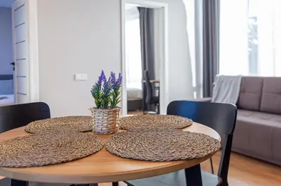 a table with pillows and a vase with purple flowers on it at Oak Park Apartment in Kaunas