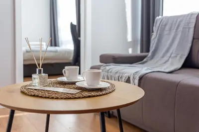 a coffee table with two cups and a couch at Oak Park Apartment in Kaunas