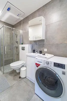 a bathroom with a washing machine and a toilet at Oak Park Apartment in Kaunas