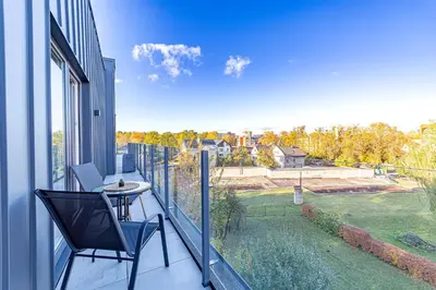 a balcony with a table and a chair on it at Oak Park Apartment in Kaunas