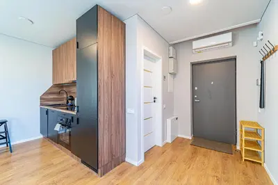 a kitchen with a black refrigerator and wooden cabinets at Oak Park Apartment in Kaunas