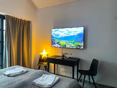 a bedroom with a bed and a desk with a television on the wall at Lakeview Modern Karaim Cottage Trakai in Trakai