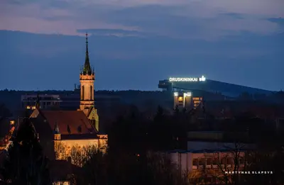 a building with a clock tower in a city at night at Drusk Sun in Druskininkai