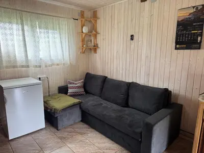 a living room with a couch and a refrigerator at Pinetree House in Gudeliai