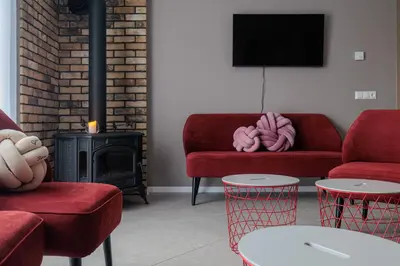 a living room with two red couches and a fire place at Sabos Rezidencija Private Countryside Villa near Vilnius in Dzenkuniskes