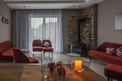 a living room with a table and a fireplace at Sabos Rezidencija Private Countryside Villa near Vilnius in Dzenkuniskes