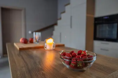 a bowl of strawberries sitting on a wooden table at Sabos Rezidencija Private Countryside Villa near Vilnius in Dzenkuniskes