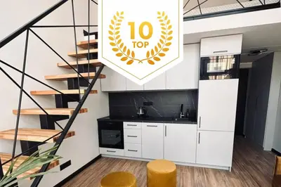 a kitchen with white cabinets and a spiral staircase at Sunny loft 24x7 x free parking x close to old town by H&H in Vilnius