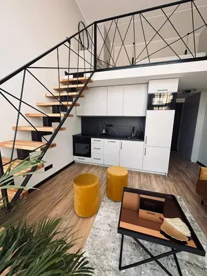 a living room with a spiral staircase and yellow stools at Sunny loft 24x7 x free parking x close to old town by H&H in Vilnius