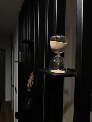 a hour glass sitting on a black shelf at Ozo Parko Butas in Vilnius