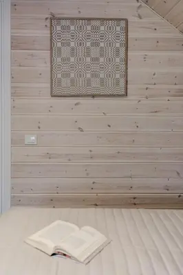a book on a bed in a room with a wall at Gamtos pinklės in Žiūrai