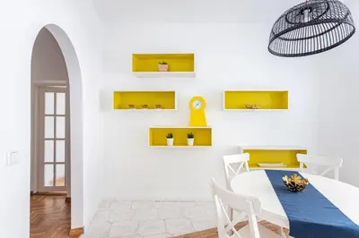 a dining room with a white table and yellow shelves at Cosy and bright Saint Ignoto Apartment by Reside Baltic in Vilnius