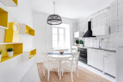 a white kitchen with a white table and chairs at Cosy and bright Saint Ignoto Apartment by Reside Baltic in Vilnius
